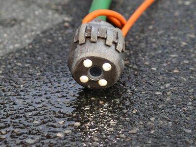 Düse für die Kanalreinigung mit integrierten LED-Lichtern auf nassem Asphalt