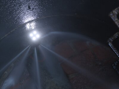 Kanaldüse mit Wasserstrahlen und LED-Beleuchtung bei der Reinigung im Schacht.